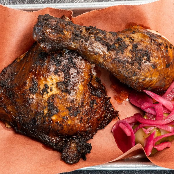 Creekside BBQ's dark, crispy smoked chicken leg and thigh with pickled red onions and cucumbers.