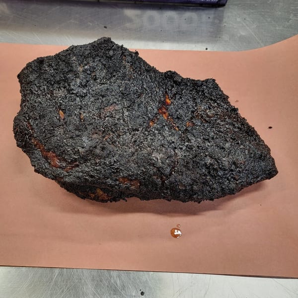 A large, dark, crusted brisket from Creekside BBQ rests on brown butcher paper.