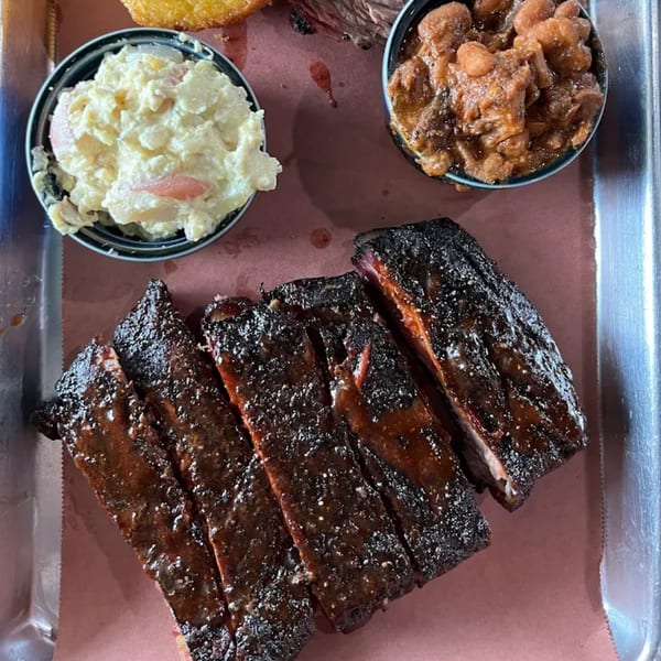 Creekside BBQ ribs with baked beans and potato salad on a metal tray.